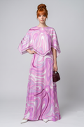 Woman wearing a pink and white patterned dress on a plain background