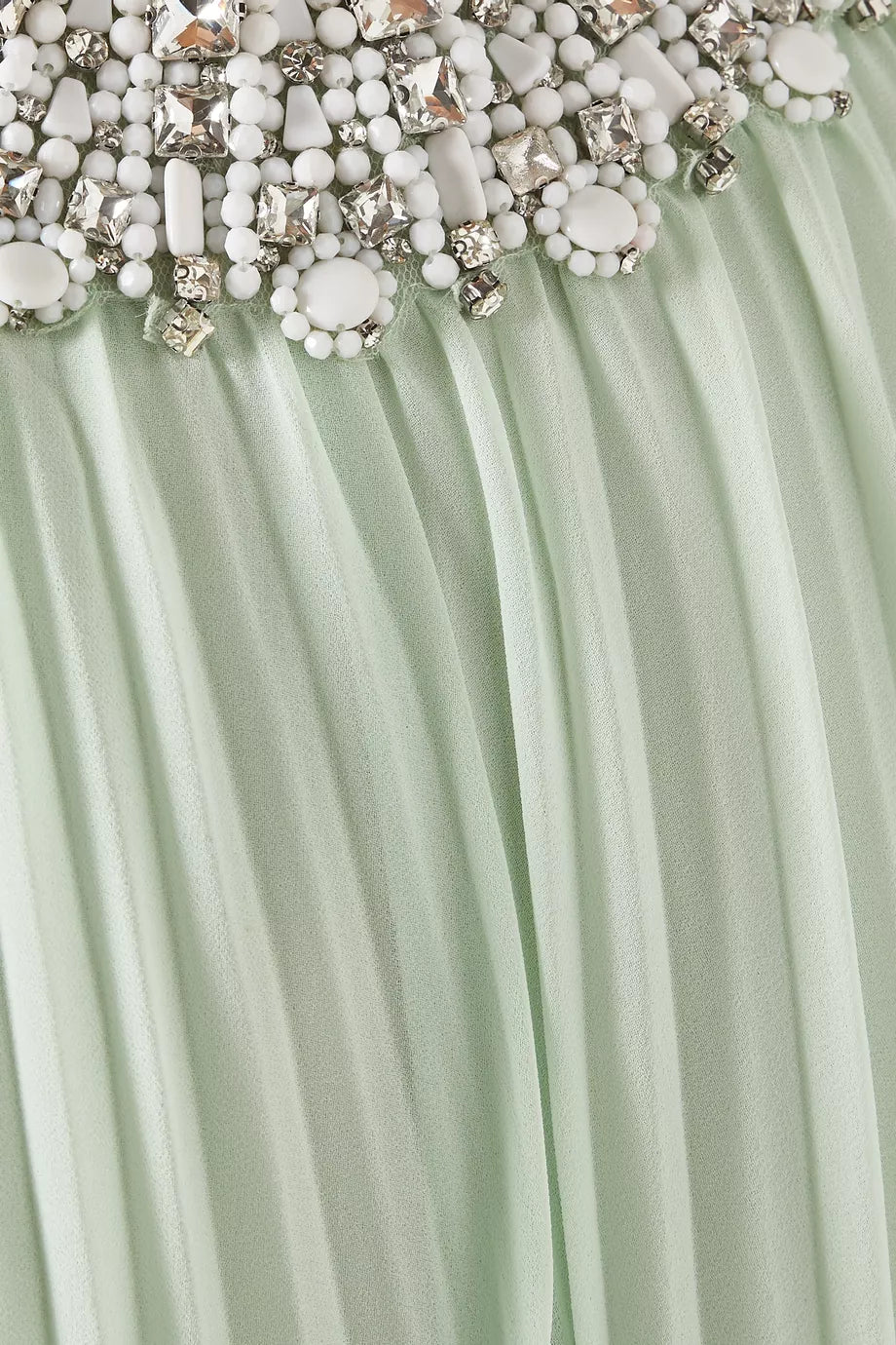 Close-up of a mint green fabric with decorative beads and crystals.