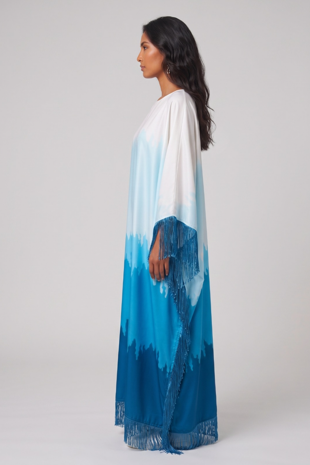 Woman wearing a long, colorful dress abaya with a gradient from white to blue on a plain background