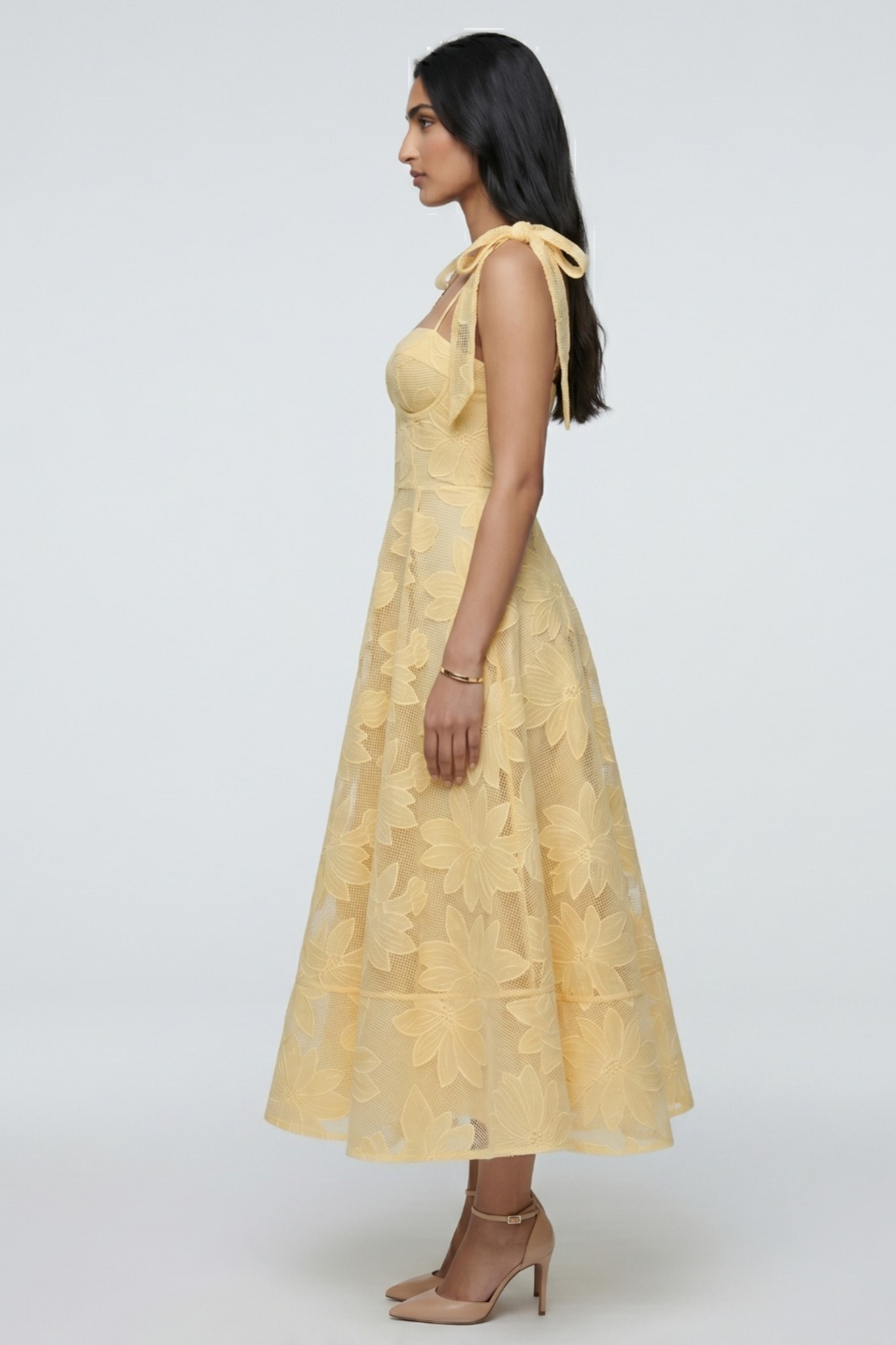 Woman wearing a yellow dress with floral patterns on a white background