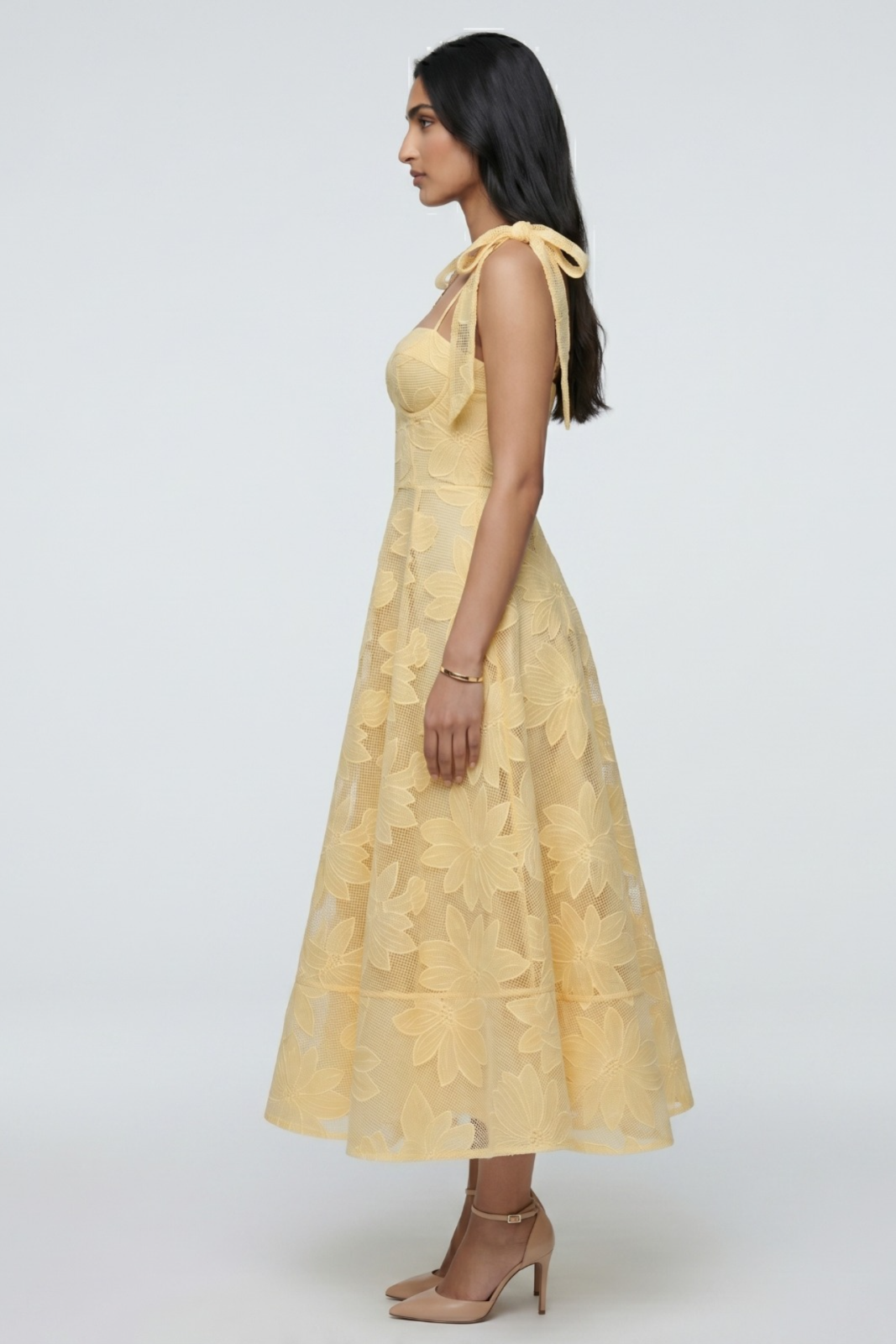 Woman wearing a yellow dress with floral patterns on a white background