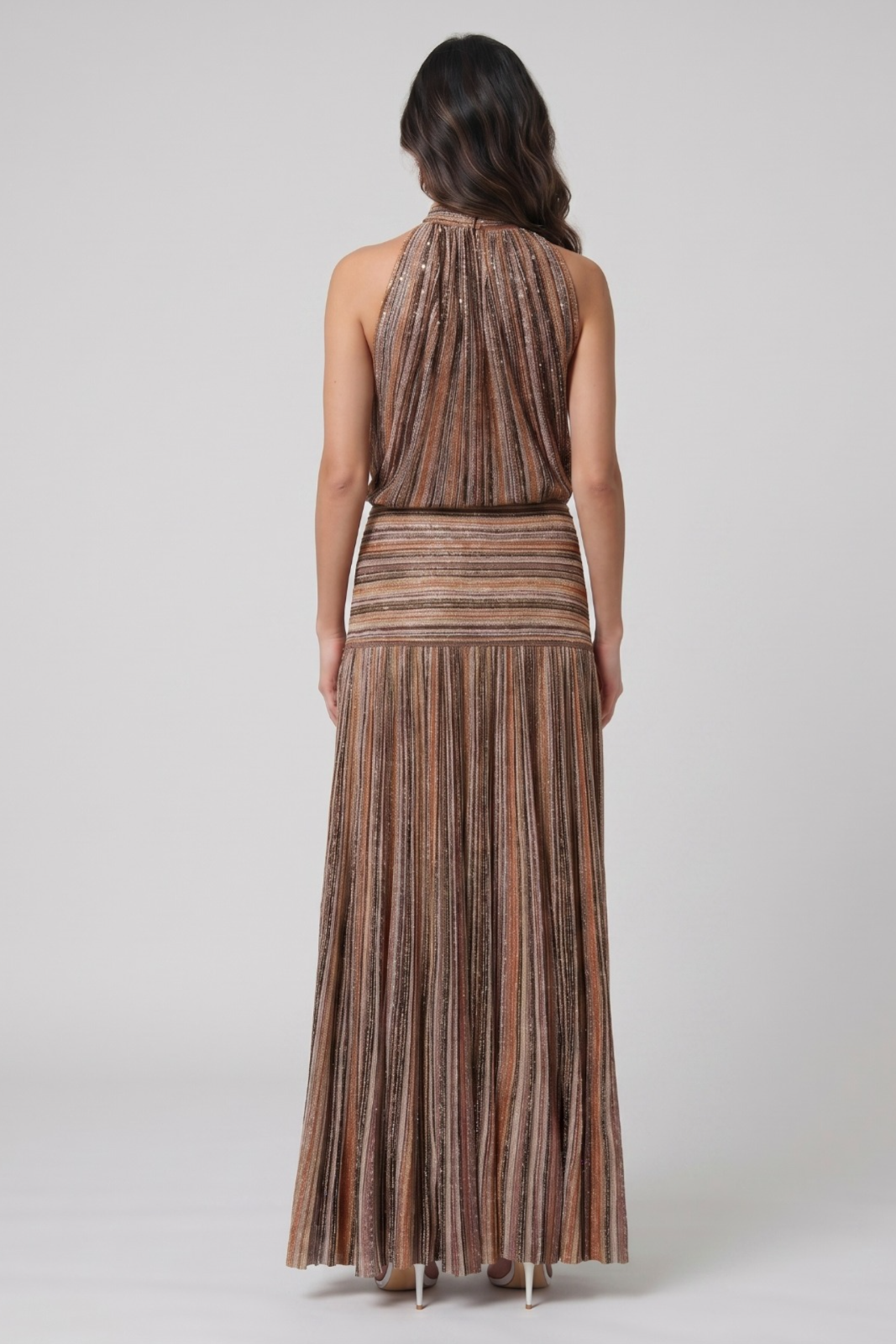 Woman wearing a patterned halter top and pleated skirt set on a white background