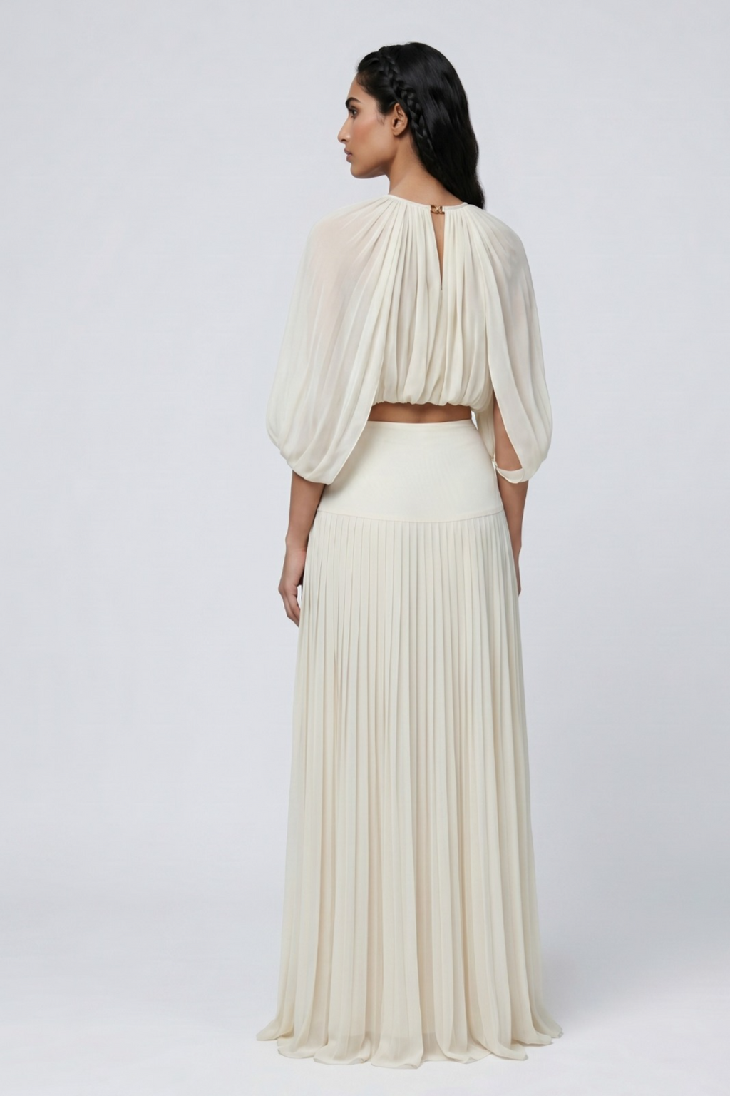 Woman wearing a flowing white dress with a plain background