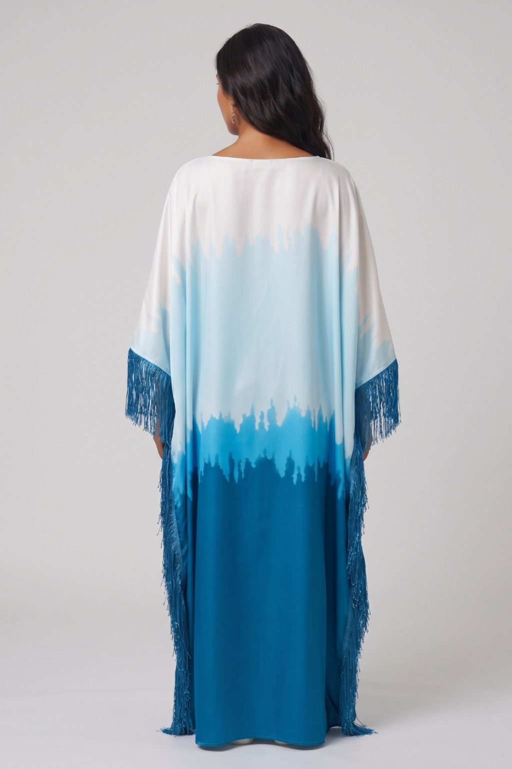 Woman wearing a long, colorful dress abaya with a gradient from white to blue on a plain background