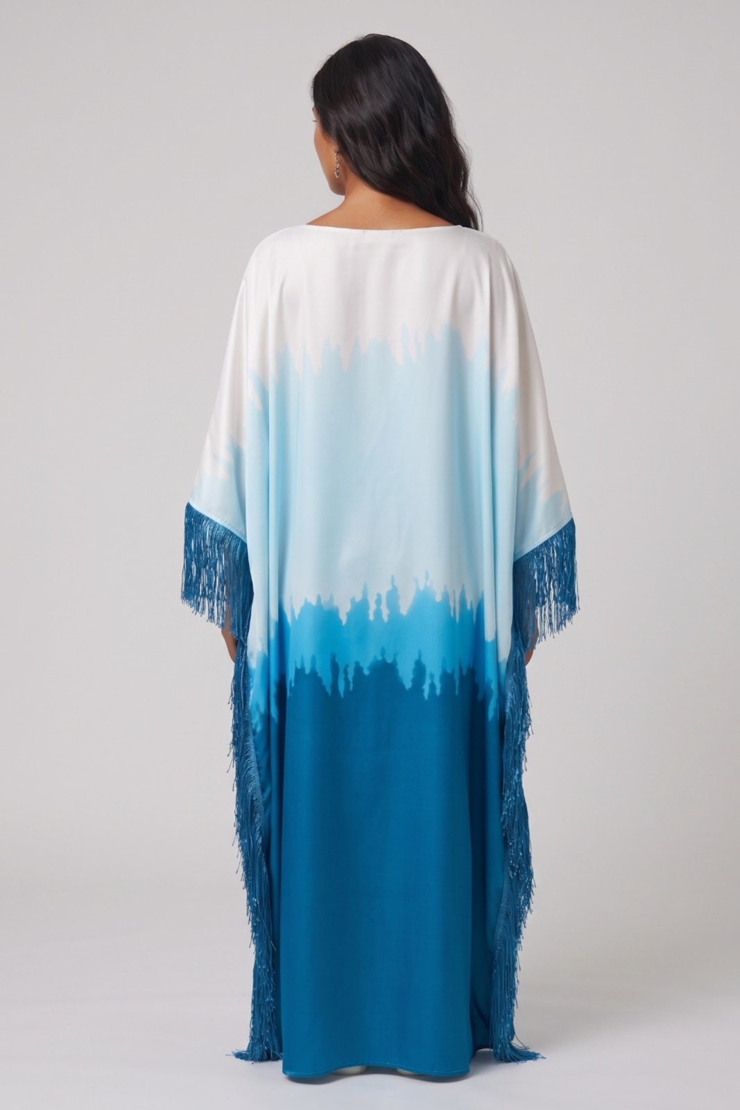 Woman wearing a long, colorful dress abaya with a gradient from white to blue on a plain background