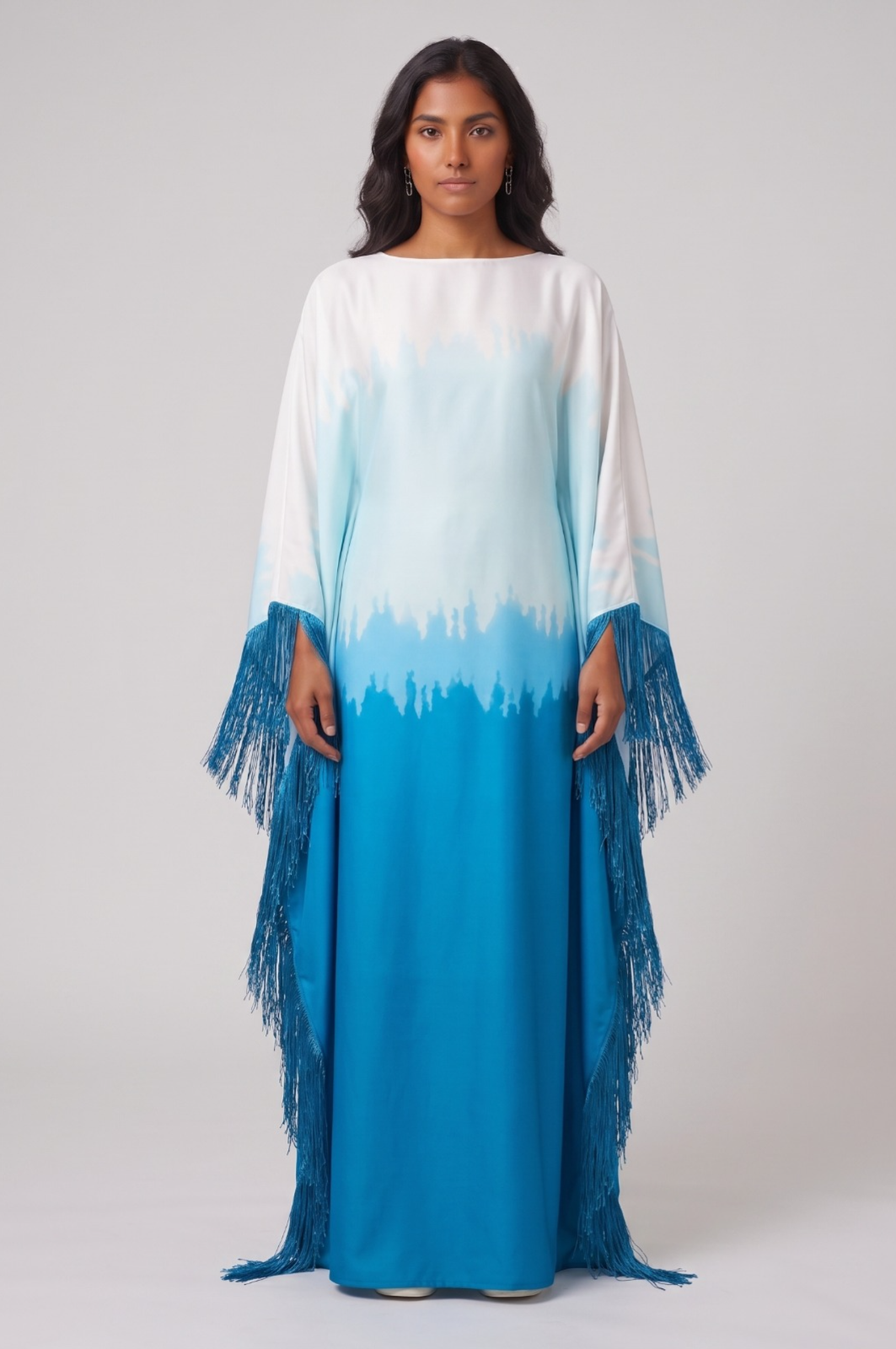 Woman wearing a long, colorful dress abaya with a gradient from white to blue on a plain background