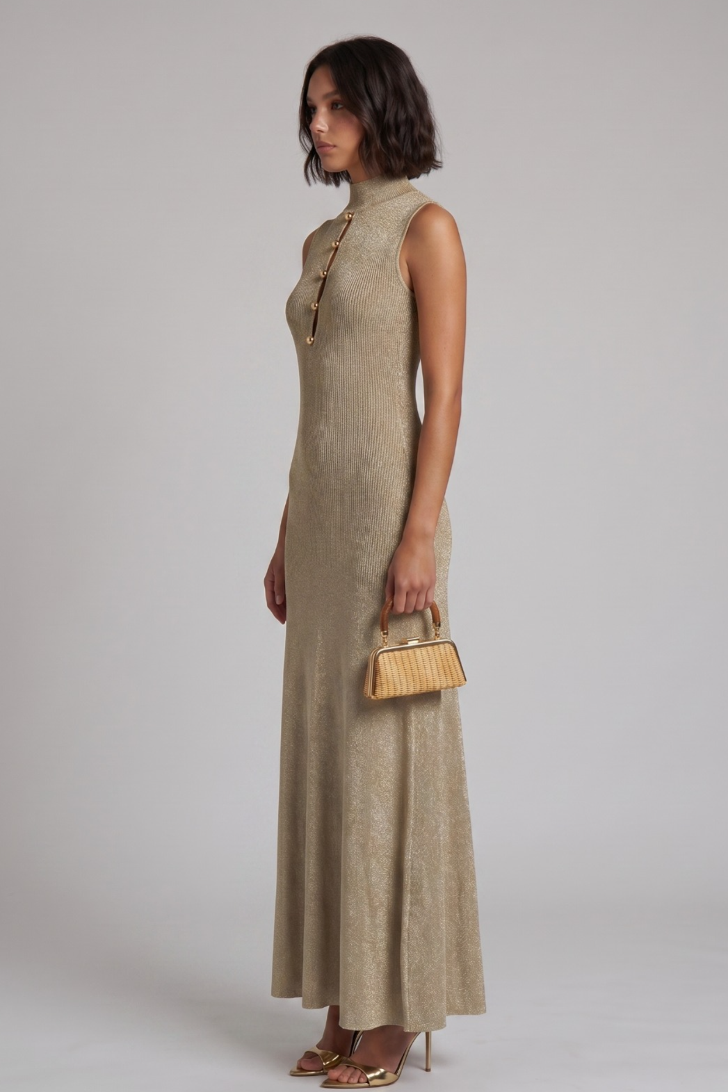 Woman wearing a long gold maxi dress against a plain background