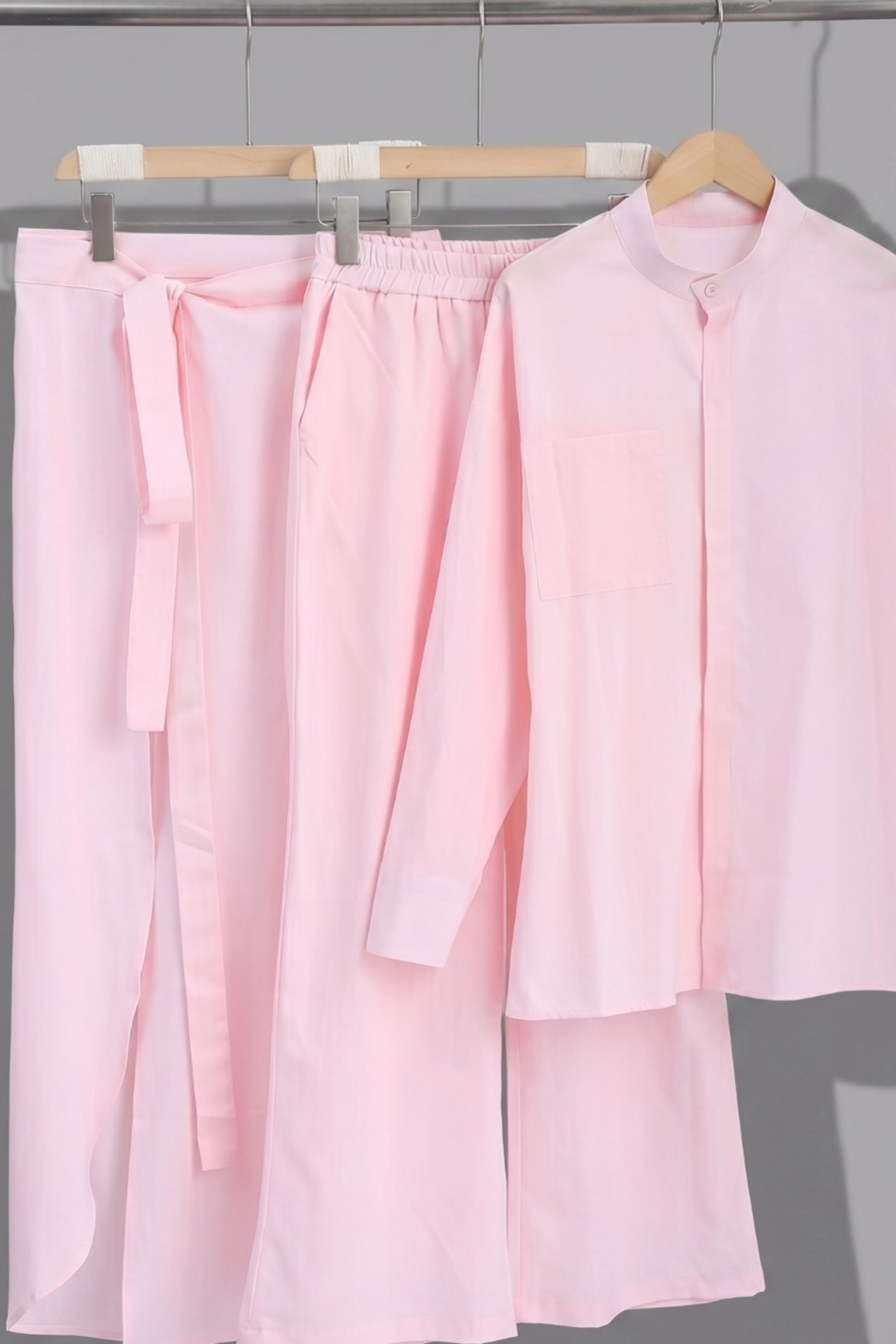Woman wearing a linen pink three piece set with a belt on a white background