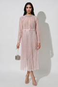 Woman wearing a pink lace dress holding a handbag against a white background